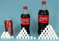 Staplade sockerbitar framför flaskor med Coca cola